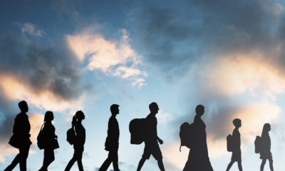 Image of immigrants in silhouette walking with luggage