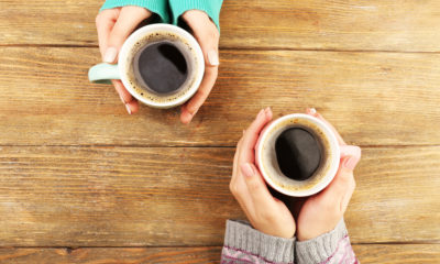 Shutterstock photo of two female hands holding cups of coffee