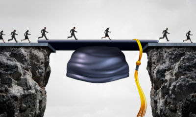 Photo of graduates crossing a gap filled by a graduation mortar cap