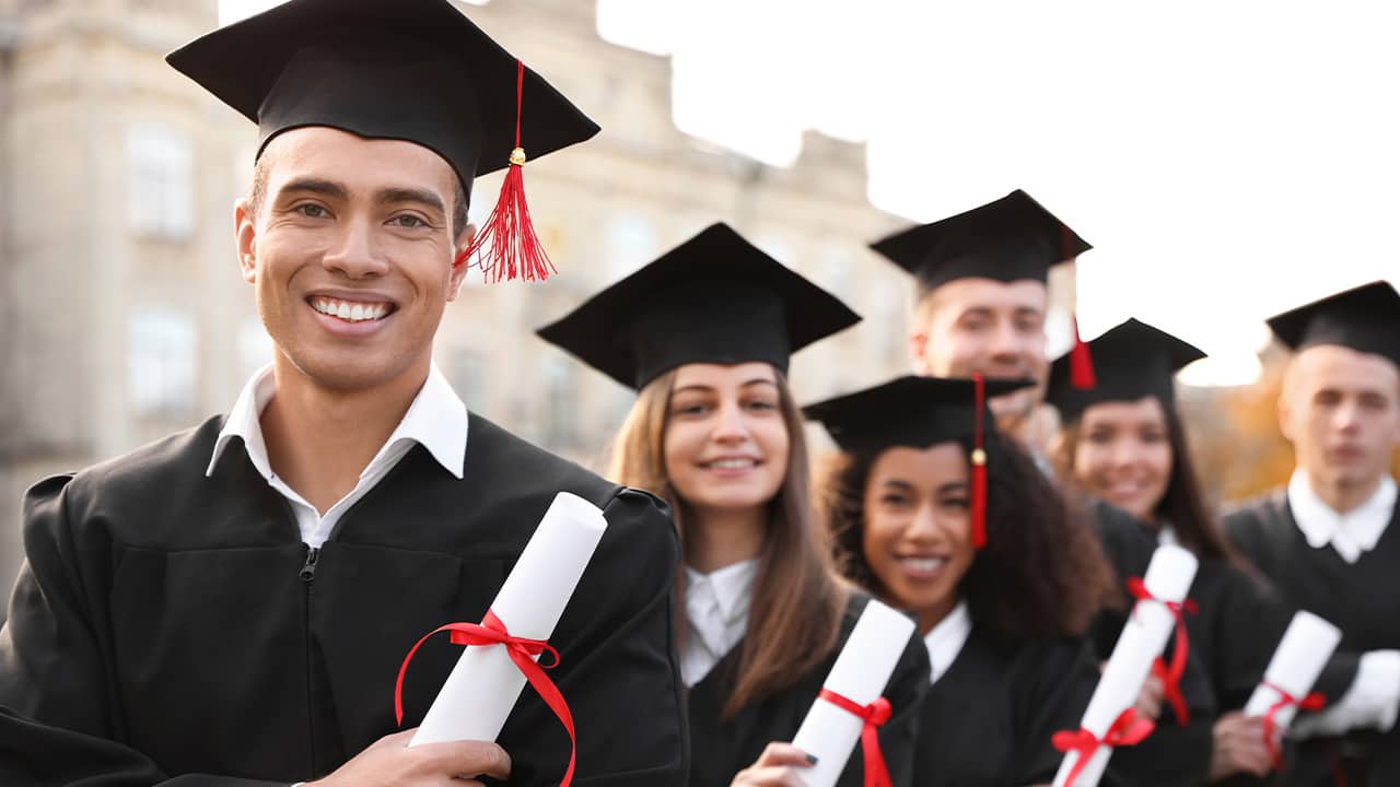 Photo of smiling college graduates holding their degrees