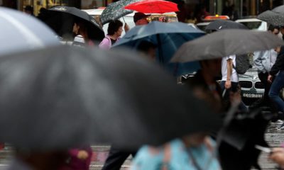 Photo of people sheltering under umbrellas in Australia