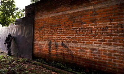 Photo of a police guard next to a graffiti wall in El Salvador