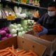 Photo of a worker stocking produce