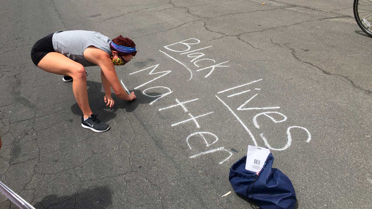 Photo of a protester writing "Black Lives Matter" in chalk on a downtown street in Fresno, California.