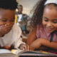 Image of two young African American students reading together