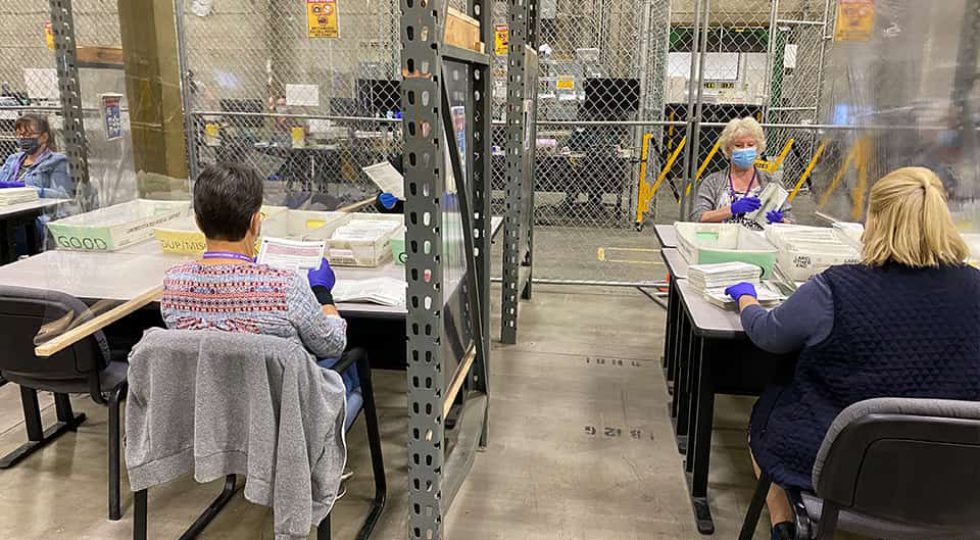 Election employees unfold the ballots by hand. (GV Wire/David Taub)